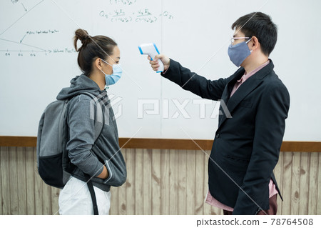 Back to school. Asian male teacher using thermometer temperature screening student for fever against the spread of COVID-19 Before entering the classroom. Virus protection concept Back to school. Asian male teacher using thermometer temperature screening student for fever against the spread of COVID-19 Before entering the classroom. Virus protection concept 78764508