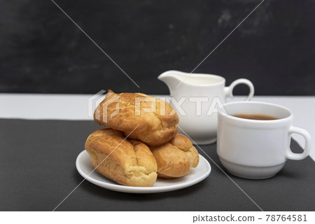 Homemade delicate profiteroles and cup of coffee. Traditional French eclairs. Side view Homemade delicate profiteroles and cup of coffee. Traditional French eclairs. Side view 78764581