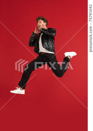 Jumping high, stylish. Young male portrait isolated on red studio background with copyspace for ad. Jumping high, stylish. Young male portrait isolated on red studio background with copyspace for ad. 78765042