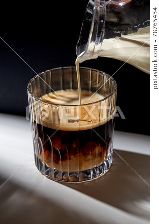 hand with jug pouring cream to glass of coffee 78765434
