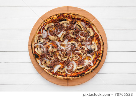 Whole round pizza on wooden plate topped with mushrooms, onion and chopped meat. Top view on white board background 78765528