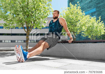 young man doing triceps dip on city street young man doing triceps dip on city street 78765686