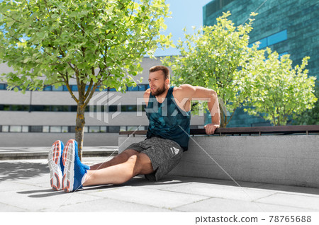 young man doing triceps dip on city street 78765688