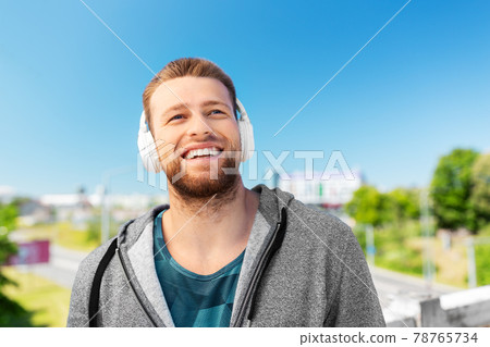 man in headphones listening to music outdoors 78765734