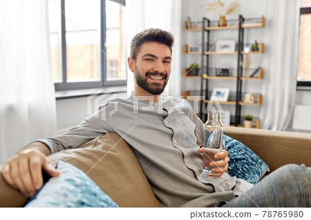 happy man drinking water from glass bottle at home happy man drinking water from glass bottle at home 78765980