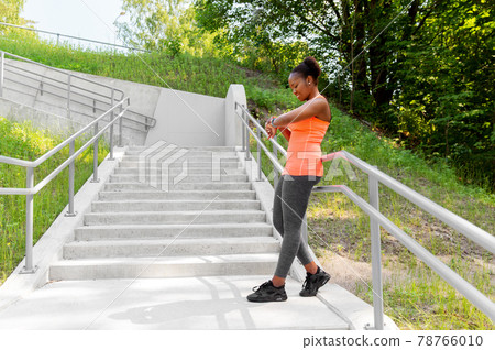 happy african woman with fitness tracker outdoors 78766010