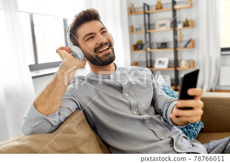 man in headphones listening to music on smartphone 78766011