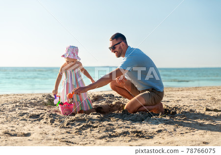 father and daughter playing with toys on beach 78766075