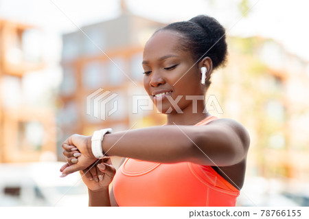 happy african woman with earphones and smart watch happy african woman with earphones and smart watch 78766155