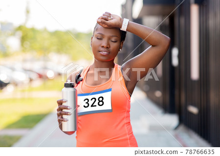 tired female marathon runner with bottle of water 78766635