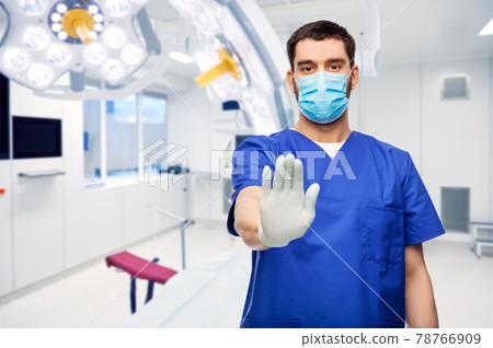 male doctor in blue uniform and mask showing stop male doctor in blue uniform and mask showing stop 78766909