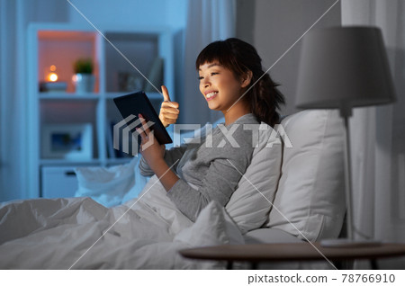 woman with tablet pc in bed has video call at night 78766910