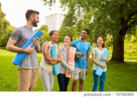 group of happy people with yoga mats at park 78766960