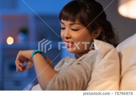 asian woman with health tracker in bed at night asian woman with health tracker in bed at night 78766978