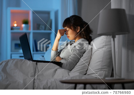 stressed woman with laptop working in bed at night stressed woman with laptop working in bed at night 78766980