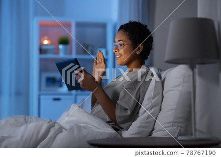woman with tablet pc in bed has video call at night woman with tablet pc in bed has video call at night 78767190