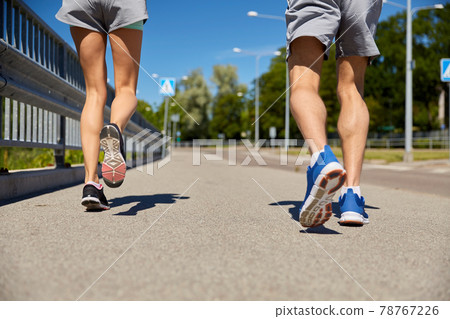 feet of sporty couple running along city road 78767226