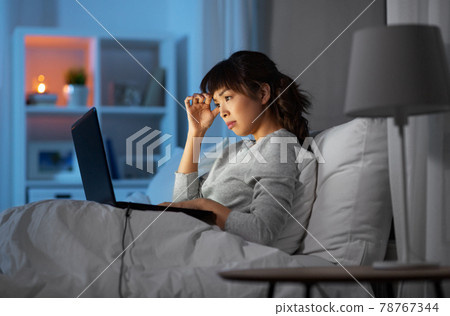 stressed woman with laptop working in bed at night 78767344