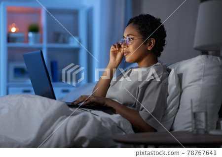 woman with laptop in bed at home at night 78767641