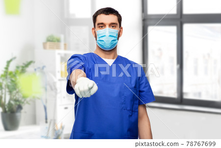 male doctor in blue scrubs and mask points finger male doctor in blue scrubs and mask points finger 78767699
