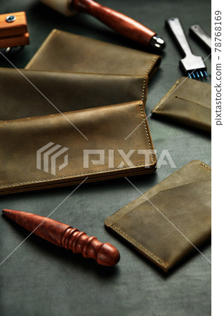 Leather products are laid out on the master's table, on a piece of leather among the tools, handmade leather accessories, leather wallets of the same color. 78768169