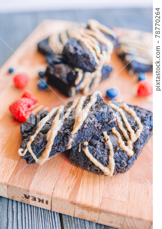 Chocolate nut brownie cake in female hands decorated with strawberries and blueberry 78770264