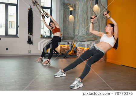 Athletic multinational people doing exercise with elastic rope in gym 78770376
