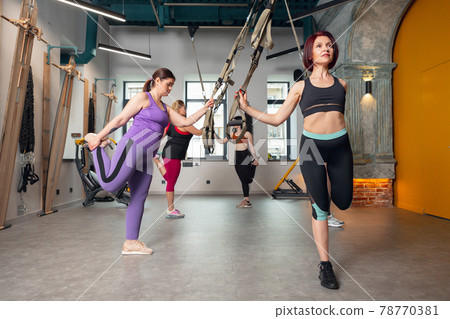 Athletic multinational people doing exercise with elastic rope in gym Athletic multinational people doing exercise with elastic rope in gym 78770381