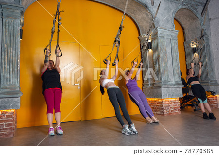 Athletic multinational people doing exercise with elastic rope in gym 78770385