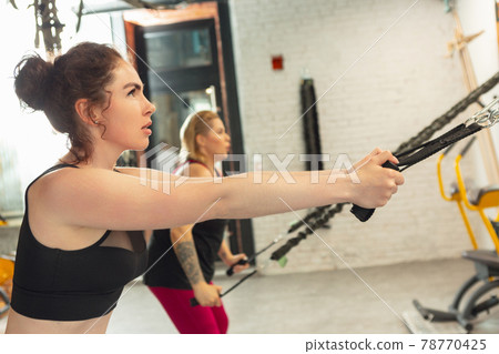 Athletic multinational people doing exercise with elastic rope in gym 78770425