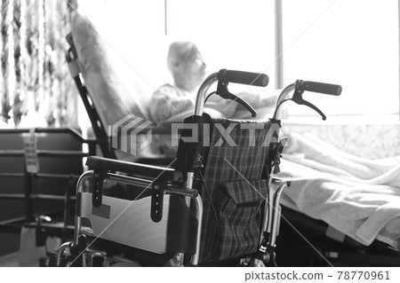 An elderly woman with dementia and a wheelchair playing with towelettes while relaxing in a nursing bed 78770961