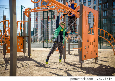 Active little child playing climbing spring metal at school yard playground. Kids play and climb outdoors under sunset, shallow Focus. Active little child playing climbing spring metal at school yard playground. Kids play and climb outdoors under sunset, shallow Focus. 78771316