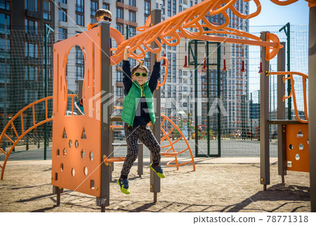 Active little child playing climbing spring metal at school yard playground. Kids play and climb outdoors under sunset, shallow Focus. 78771318