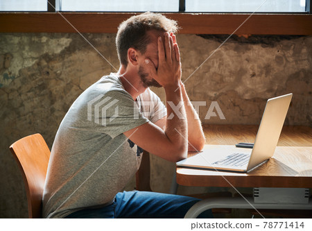 Upset man with hands on face tormented by work. Upset man with hands on face tormented by work. 78771414
