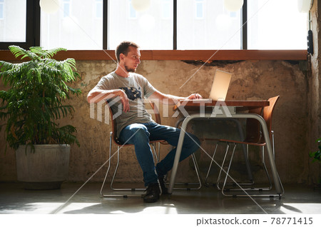 Man is sitting in cafe and working on laptop. Man is sitting in cafe and working on laptop. 78771415