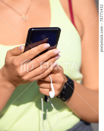 Female hands with smartphone close-up. She chooses music for her morning run. 78771432