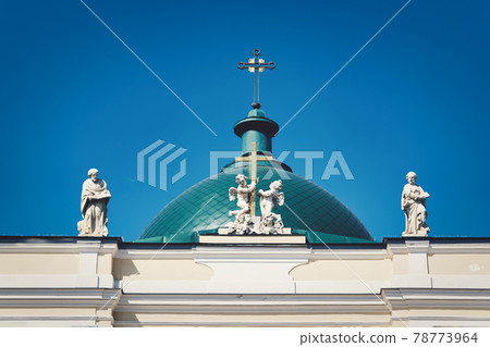 Green dome with a cross and a roof with sculptures against the blue sky Green dome with a cross and a roof with sculptures against the blue sky 78773964