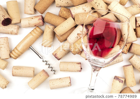 Glass of red wine with corks and corkscrew on a white background 78774989