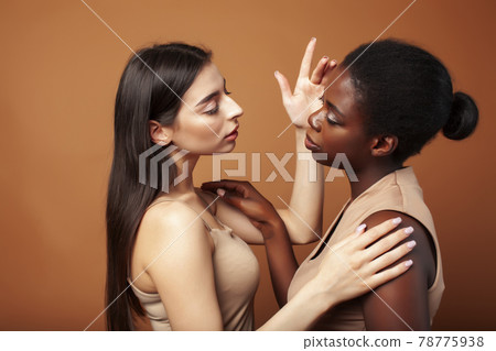 young pretty asian, afro woman posing cheerful together on brown background, lifestyle diverse nationality people concept young pretty asian, afro woman posing cheerful together on brown background, lifestyle diverse nationality people concept 78775938