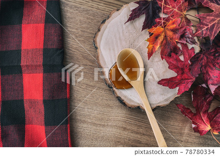 Maple syrup in wooden spoon top view over dining table wood log. Quebec local food traditional tree harvest on buffalo background. Canada grade A amber liquid from sugar shack cabane a sucre farm Maple syrup in wooden spoon top view over dining table wood log. Quebec local food traditional tree harvest on buffalo background. Canada grade A amber liquid from sugar shack cabane a sucre farm 78780334