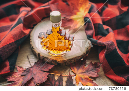 Maple syrup gift bottle in red maple tree leaves for tourist souvenir. Canada grade A amber sweet natural liquid from Quebec sugar shack maple trees farm 78780336