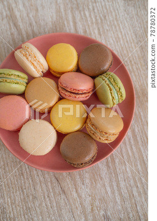 Macarons top view on pink plate against wooden background retro cute desserts. Selections of pastel color macaron 78780372