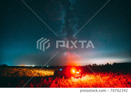 Milky Way Galaxy In Night Starry Sky With Glowing Stars Above Car SUV In Countryside Landscape. Milky Way Galaxy And Rural Field Meadow 78782342
