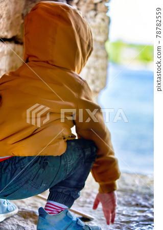 A child sits on his haunches in the observation window of the fortress A child sits on his haunches in the observation window of the fortress 78782559