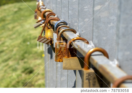 Rusty old padlocks hang in a row on the railing close up Rusty old padlocks hang in a row on the railing close up 78783058