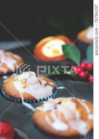 Orange and cherry muffins in muffin baking pan 78784287