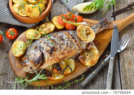 Grilled gilthead sea bream with herbs, lemon slices and rosemary potatoes Grilled gilthead sea bream with herbs, lemon slices and rosemary potatoes 78786684