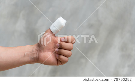 A thumb of men is injured on a gray background. 78790292