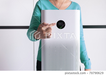 Woman hands pointing to screen of white modern air purifier in a living room for refresh air flow at home,Advanced air purifying and protect Pm2.5 78790629