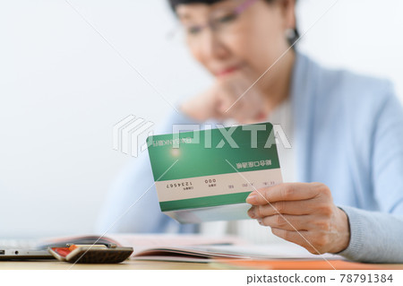 Senior woman thinking by looking at her passbook Senior woman thinking by looking at her passbook 78791384